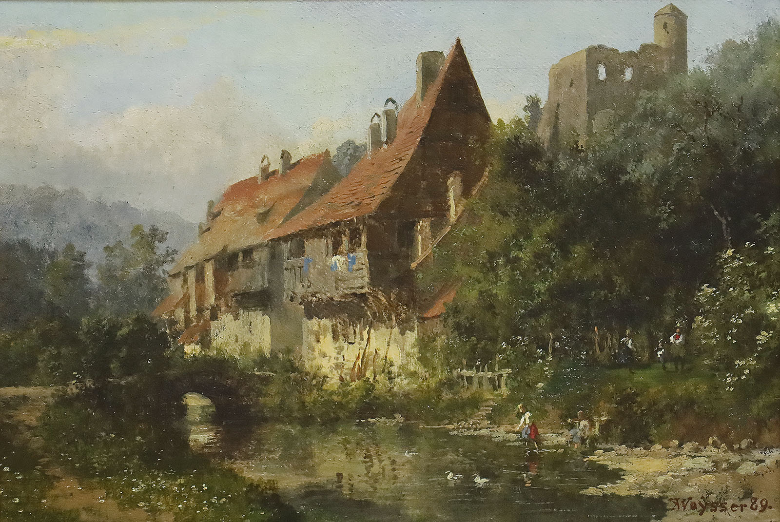 Häuser an einem Flüsschen unterhalb einer Burgruine.