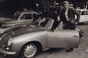 Der Sänger Johnny Halliday, bei einem Porsche Cabriolet stehend.